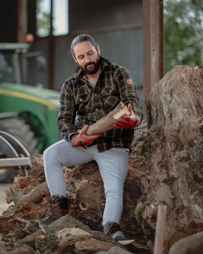 Man holding firewood wearing the New Forest Padded Shirt, a stylish made padded shirt