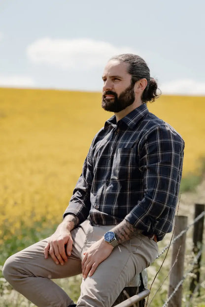 Man sitting on fence wearing the New Forest Premium Tattersall Shirt in forest premium style