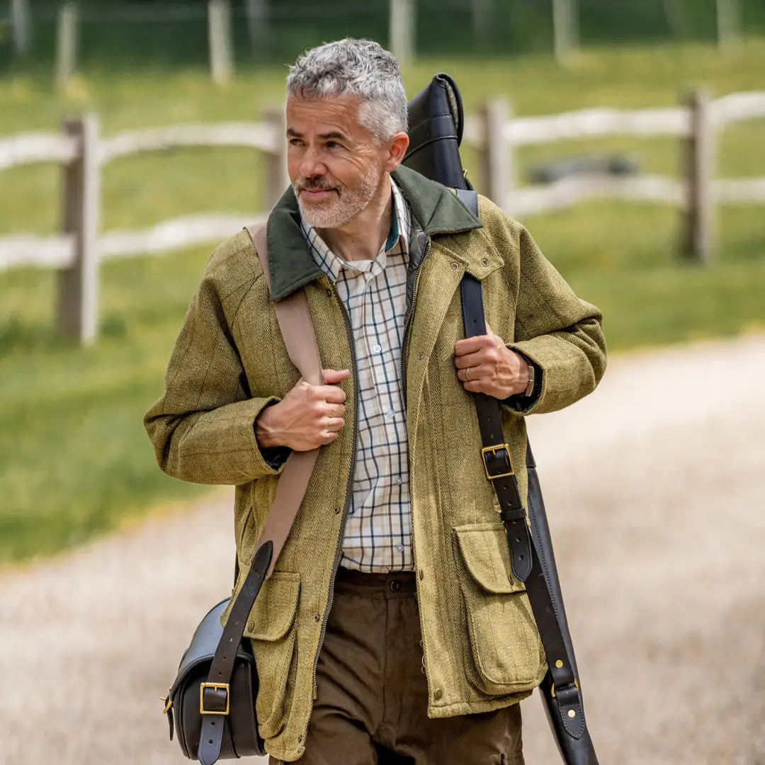 Middle-aged man in a green hunting jacket with a gun case wearing a Premium Tattersall Shirt