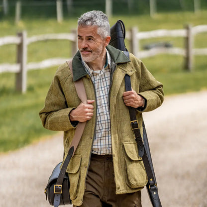 Middle-aged man in a green hunting jacket with a gun case wearing a Premium Tattersall Shirt