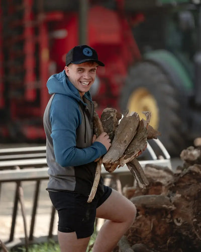 Smiling man wearing New Forest Raptor Hoodie carrying firewood in the forest