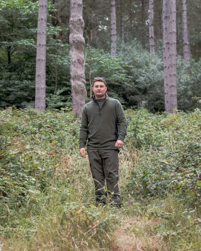 Man in olive green New Forest Trail Fleece outdoors in forest trail gear