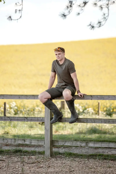 Man sitting on a fence wearing New Forest Trail Shorts perfect for forest trail adventures