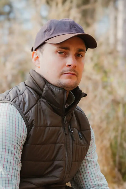 Man in a brown vest and cap rocking the New Forest Wax Baseball Cap style