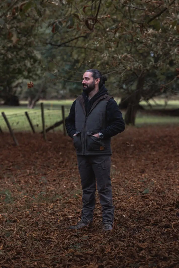 Man with beard in forest woodland trousers and vest showcasing button fastening offers