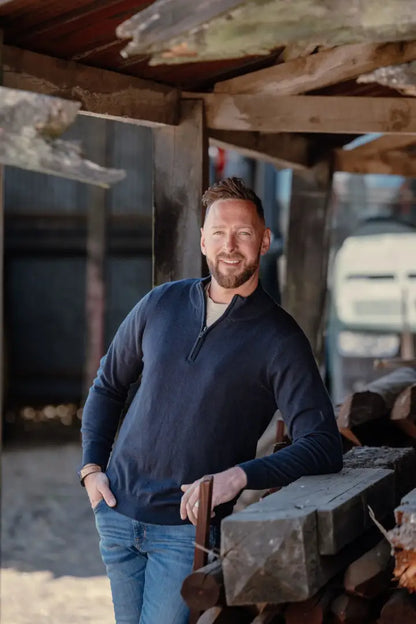 Smiling man wearing New Forest Zip Neck Jumper, a stylish blue zip neck jumper