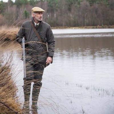 Man in traditional hunting gear by a lake wearing Percussion Sologne Neoprene Wellington Boots