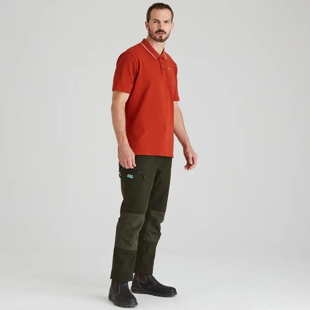 Man wearing a Ridgeline Kilworth Polo Top in rust and green for a casual look
