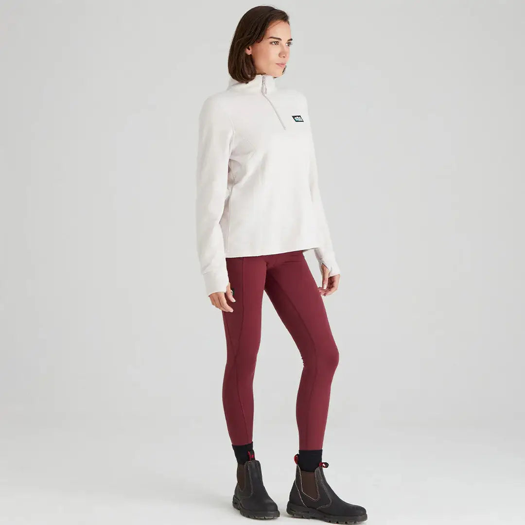Woman in Ridgeline Ladies Narvik Fleece wearing white quarter-zip and maroon leggings