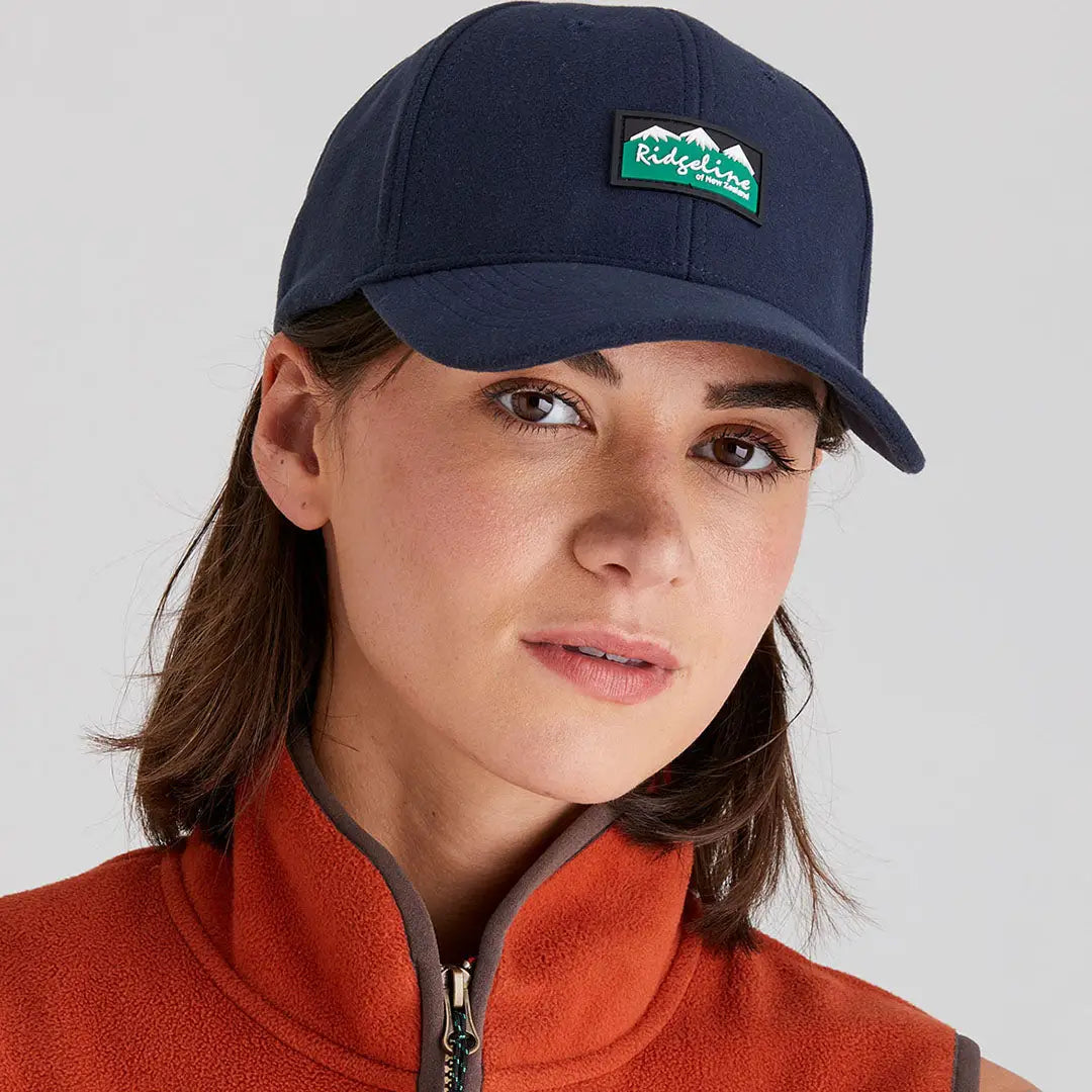 Woman wearing Ridgeline Monsoon Classic Cap with mountain patch and orange fleece vest