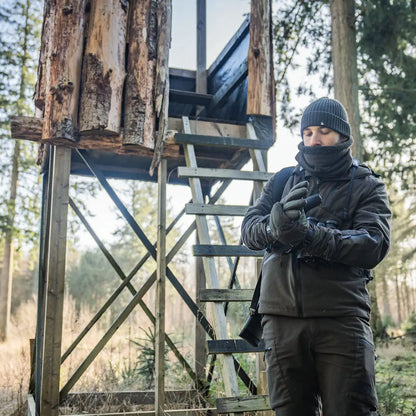 Hunter with binoculars near a hunting blind wearing Seeland Celsius Heat Gloves for warmth