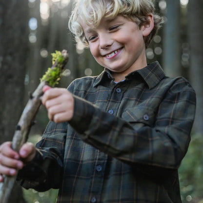 Smiling boy wearing Seeland Glen Junior Flannel Shirt holding mossy stick outdoors