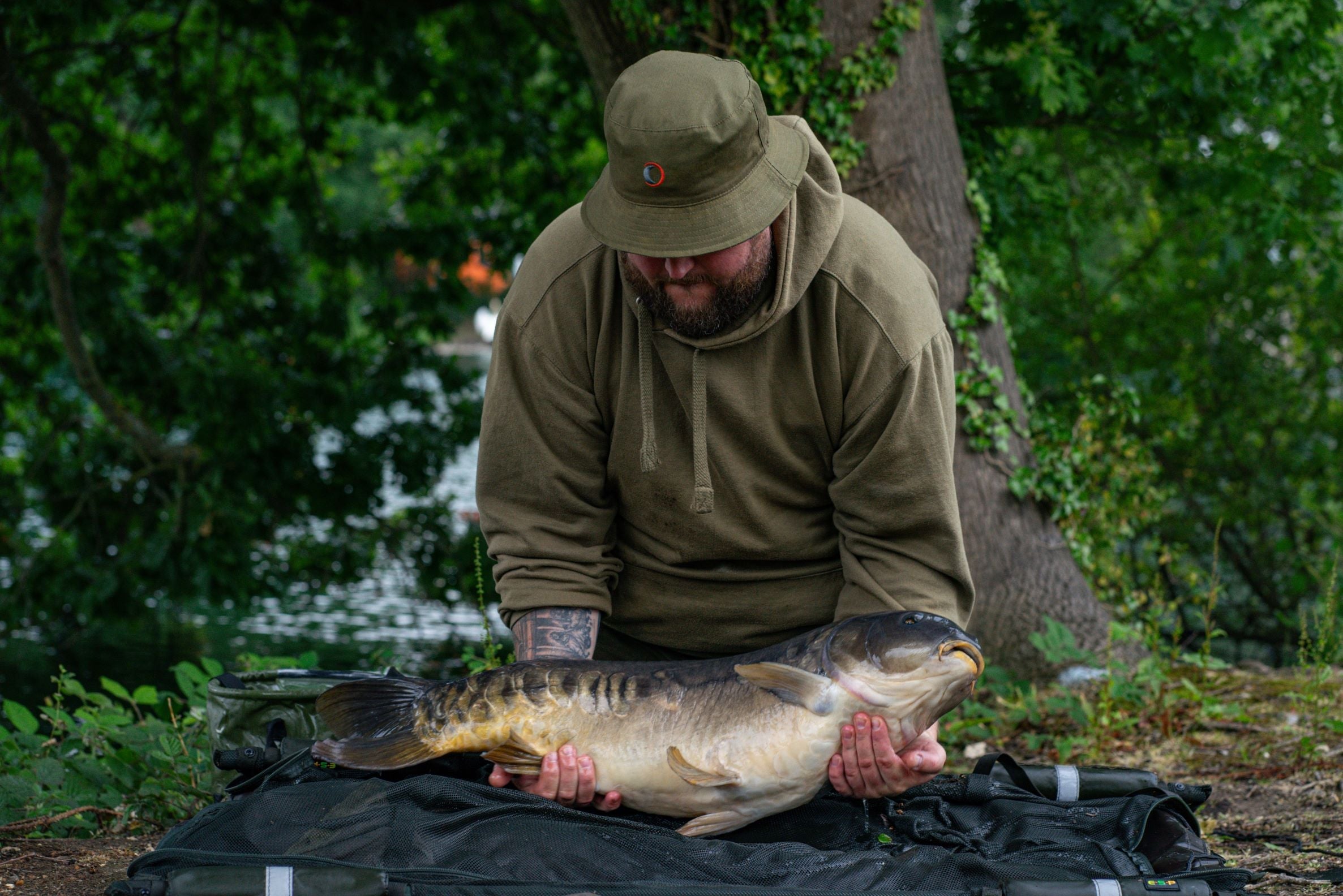 Man with a big carp wearing a Speero Reversible Bucket Hat for fishing adventures