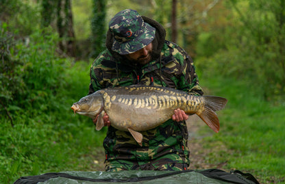 Fisherman proudly holding carp while wearing a Speero Reversible Bucket Hat