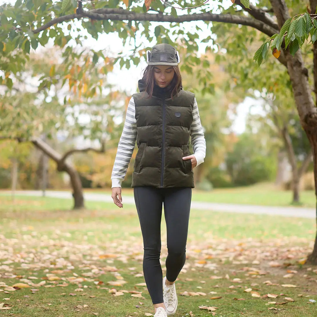 Woman in dark green puffer vest and striped shirt wearing Swanndri Birchwood Sherpa Lined Cap