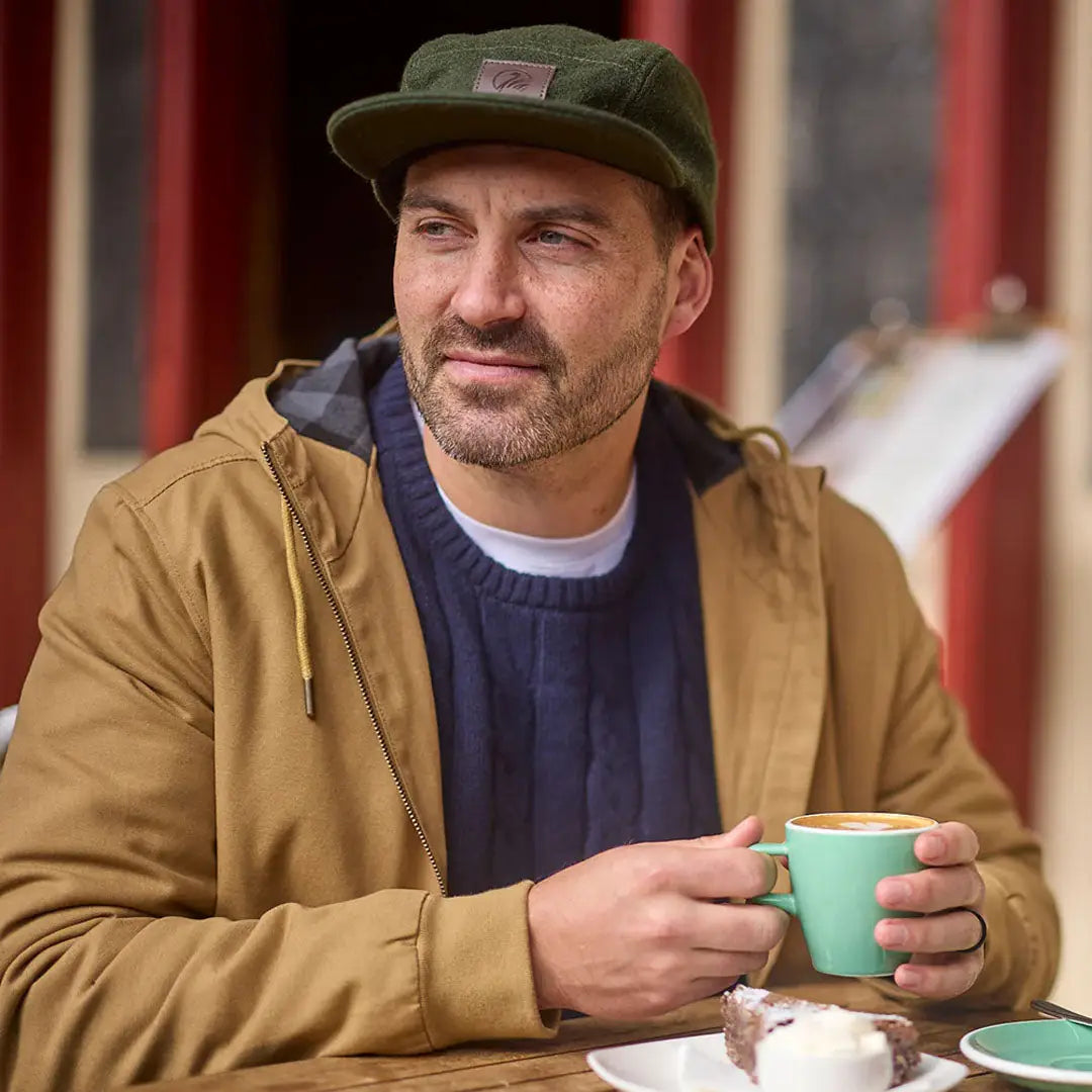 Man in a cap and jacket enjoying coffee wearing Swanndri Doncaster Mens Cable Knit Crew