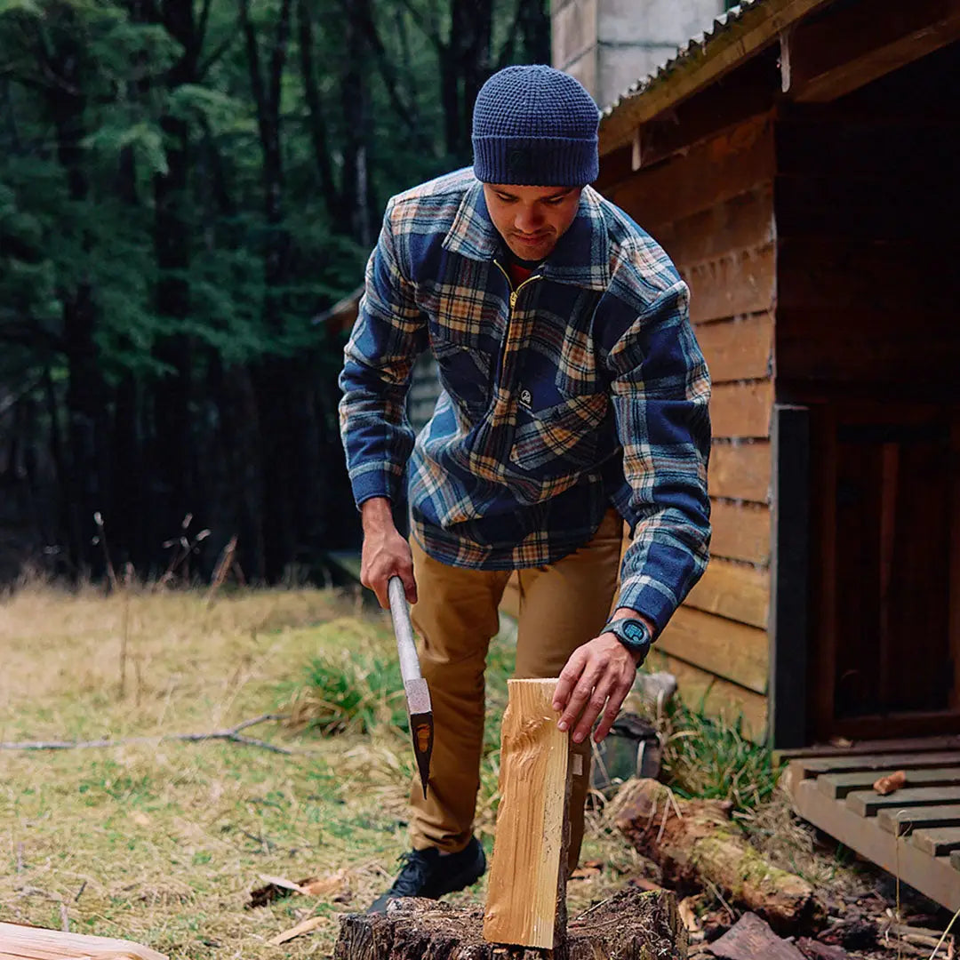 Man in blue plaid Swanndri Ranger Wool Zip Front Bushshirt splitting wood outdoors