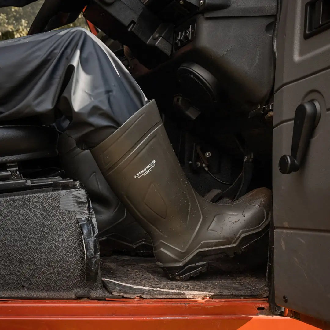 Person’s leg in swampmaster pro knee-high rubber boot inside vehicle for hunting country clothing